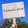 Schild mit aufgemalter Schrift "Demokratie"