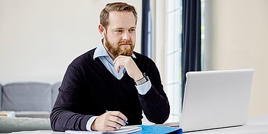 Foto Mann mit Bart am Schreibtisch vor Laptop