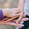 Foto: Hände übereinander, ganz oben eine kleine Kinderhand