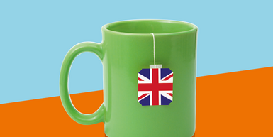 Bild grüne Tasse mit britischem Teebeutel vor orange-hellblauem Hintergrund