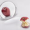 angebissener "dünner" Apfel spiegelt sich in einem Spiegel als runder Apfel