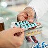 Foto: Hand eines Apothekers, der eine Packung Tabletten überreicht