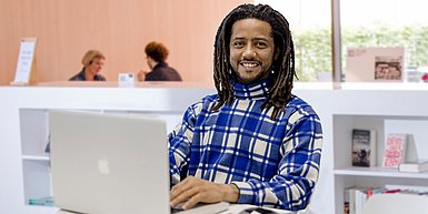 Junger Mann mit schwarzen Locken vor Laptop