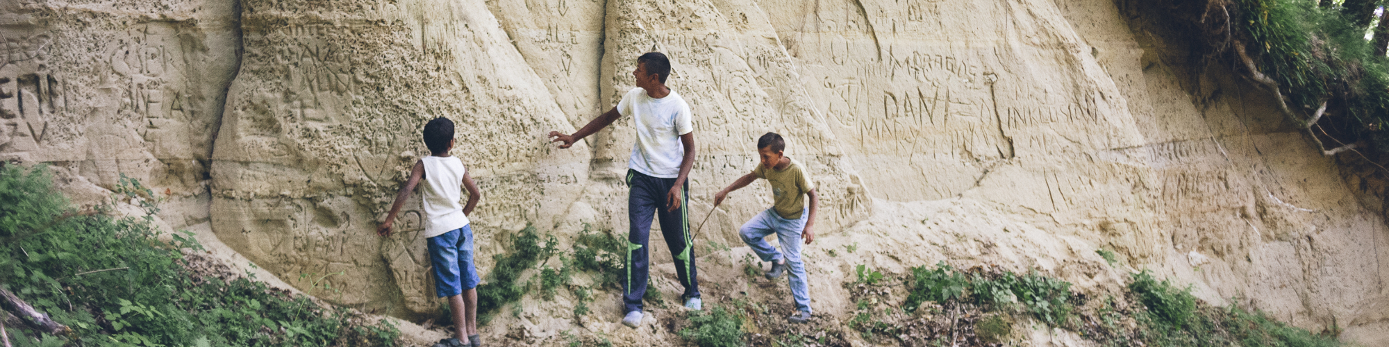 junger Mann und zwei Kinder vor einer Felswand